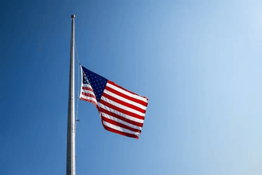 American flag flying at half-staff on a clear day